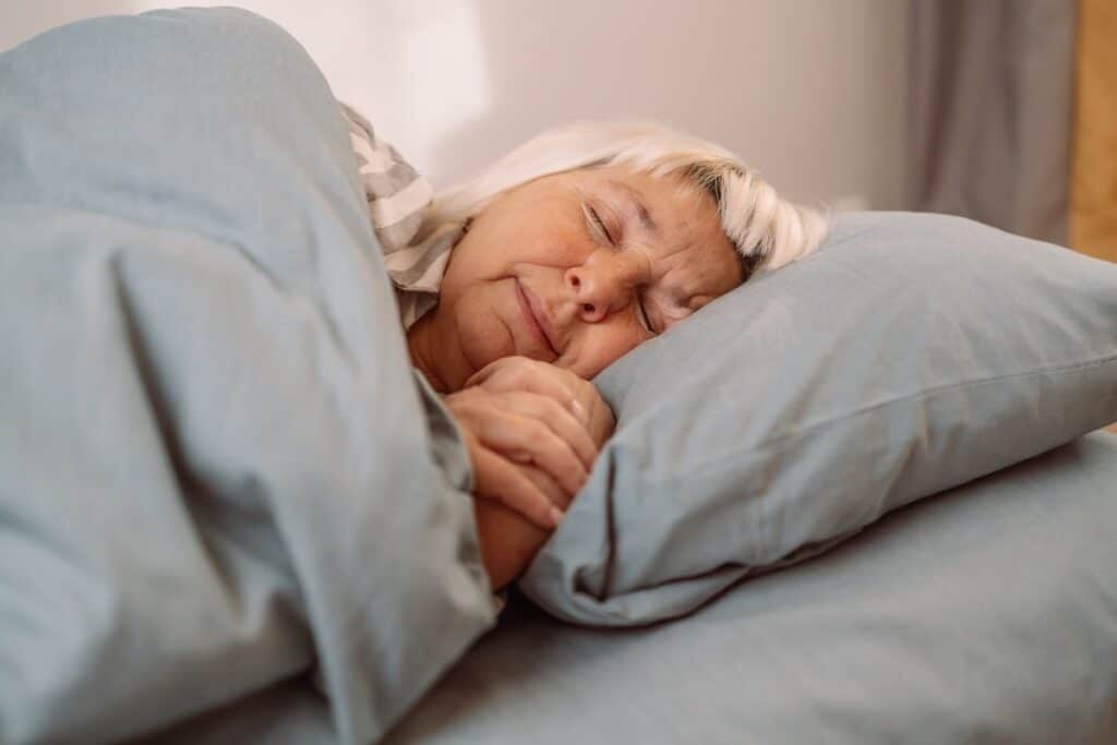 Older woman happily sleeping in her bed